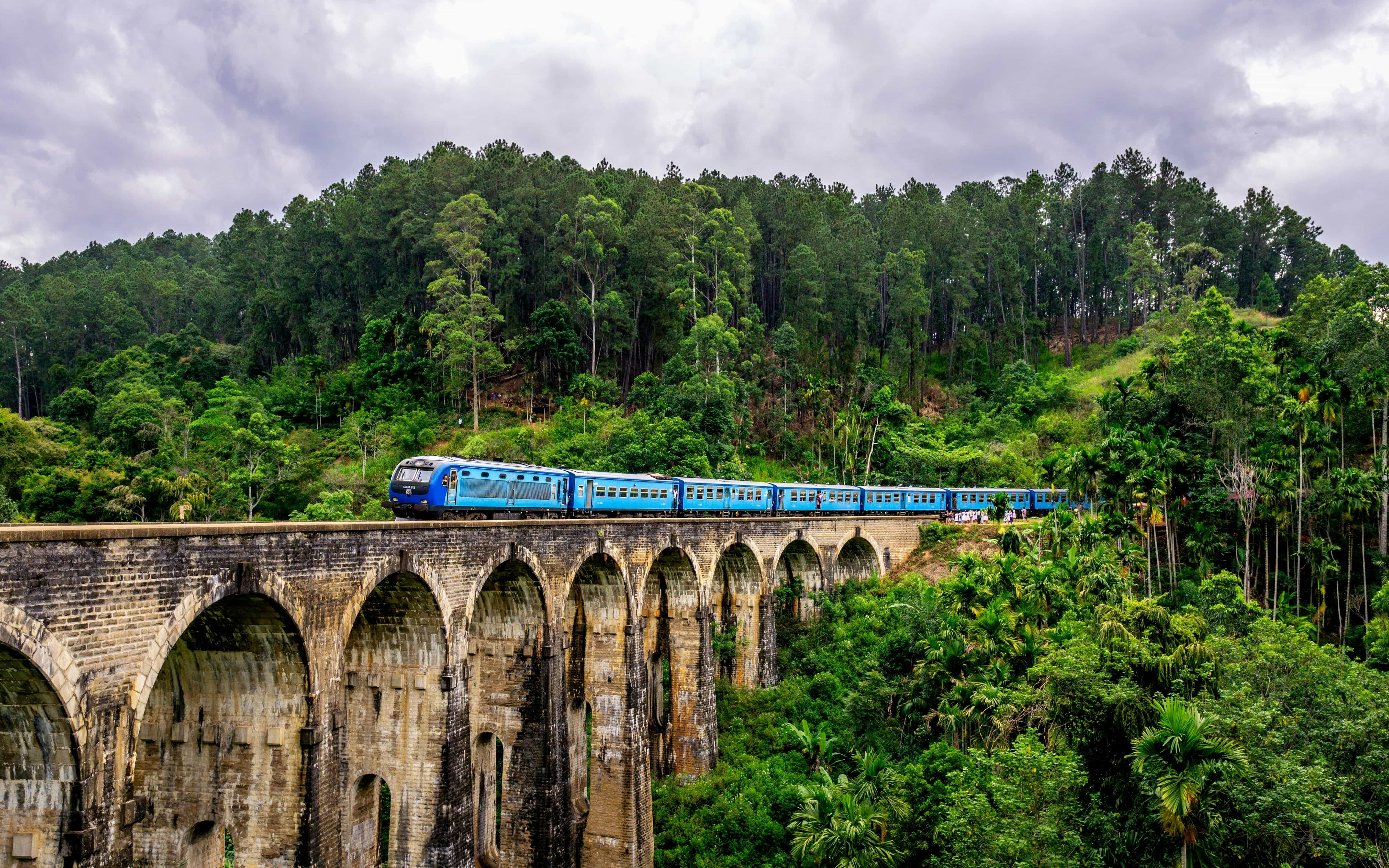 Scenic blue train crossing the Nine Arch Bridge in Ella, Sri Lanka with lush green jungle views – AASH Travels